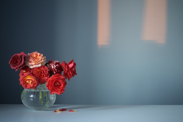 Premium Photo | Red roses in glass vase on blue background