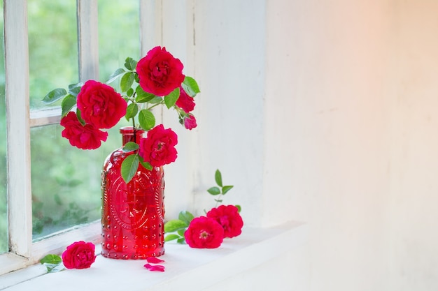 窓辺に赤いガラスの花瓶の赤いバラ プレミアム写真