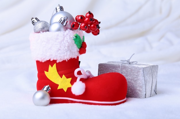 雪の背景にクリスマスプレゼントと赤いサンタさんのブーツ 幸せな休日の組成 プレミアム写真