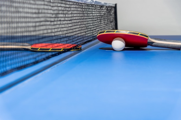 Premium Photo | Red table tennis racket and a white ball on the blue ...