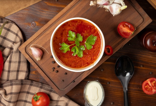 Red tomato, borsh vegetable soup in disposable cup bowl served with green vegetables Free Photo