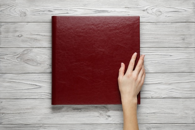 Red wedding photo book with leather cover. stylish wedding photo album close up. person opens a ...