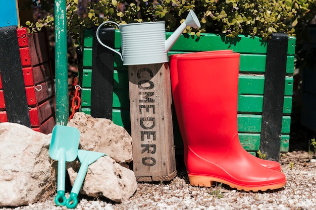 Red wellington boots; watering can 