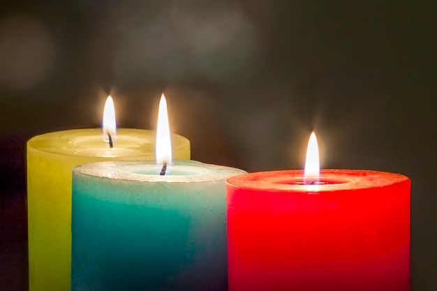 Red, yellow and green colourful candles with blurred bokeh background. christmas and new year copy space. Premium Photo