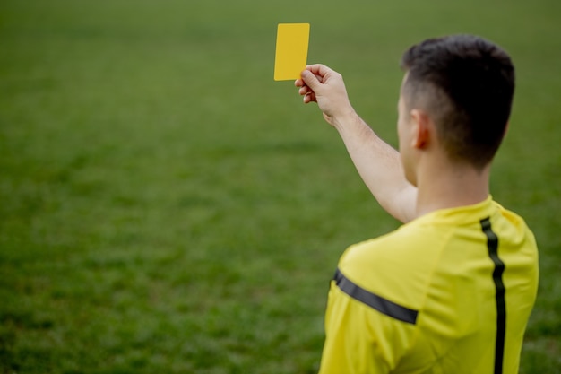 ゲーム中に不快なサッカー選手またはサッカー選手にレッドカードを見せている審判 プレミアム写真