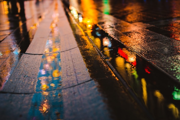 Premium Photo | Reflections of city lights on the wet road surface.