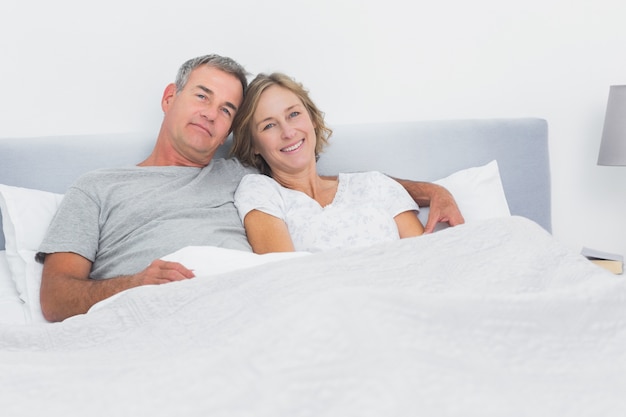 Premium Photo | Relaxed couple cuddling in bed looking at camera