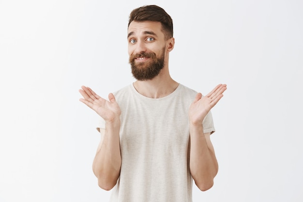 Free Photo | Reluctant smiling bearded man posing against the white wall