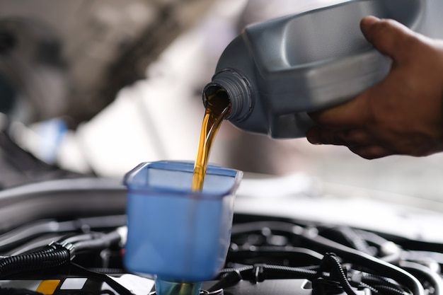 Premium Photo | Repairman pouring motor oil into car engine closeup