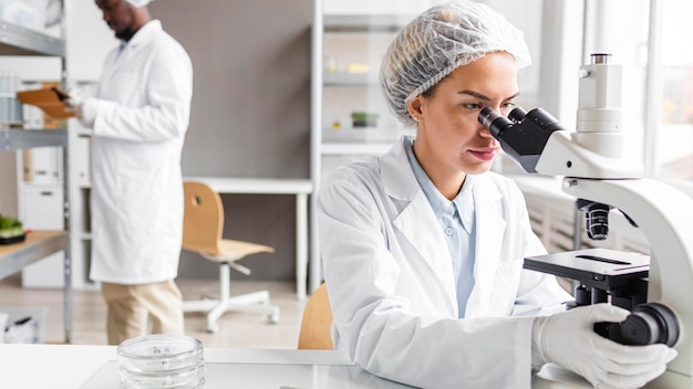 Researchers in the biotechnology laboratory with tablet and microscope Free Photo