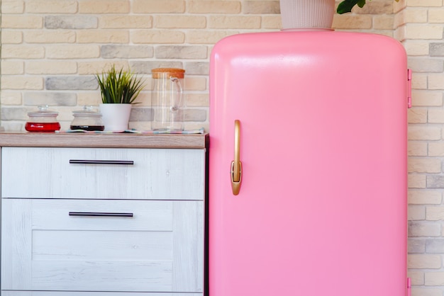 ビンテージキッチンでレトロなスタイルのピンクの冷蔵庫 プレミアム写真