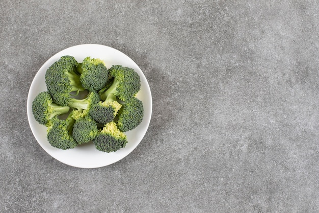 Ripe broccoli on a plate, on the marble table. Free Photo