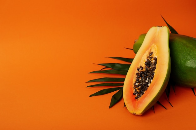 Premium Photo | Ripe papaya with leaves on orange background