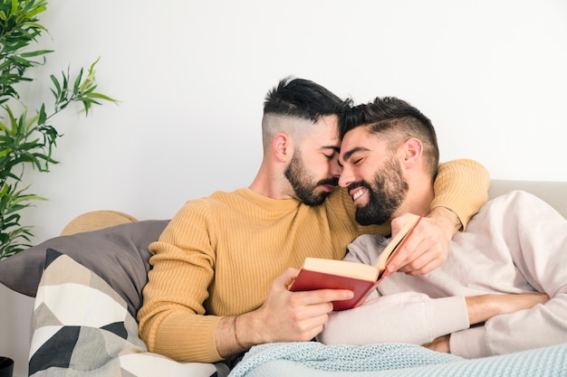 Free Photo | Romantic gay couple lying on sofa against the white wall