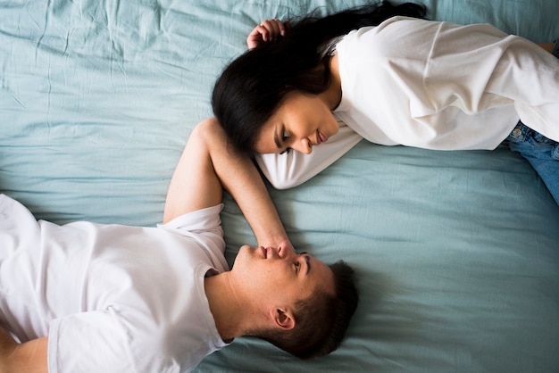 Romantic loving couple lying on bed and looking into eyes Free Photo