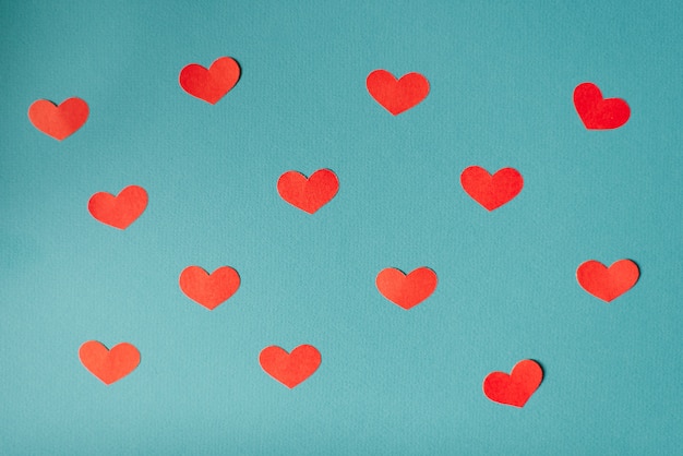 ロマンチックなバレンタインデーの背景 かわいい心フラット横たわっていた シンプルなバナーの壁紙デザイン 赤い紙は 青の背景に心をカット プレミアム写真