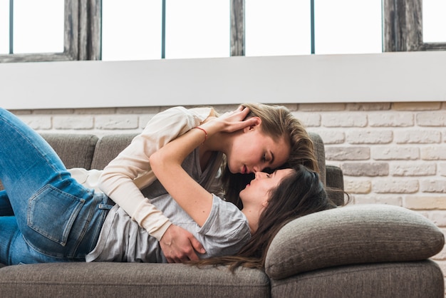 Lesbian couple kissing on sofa stock photos and images