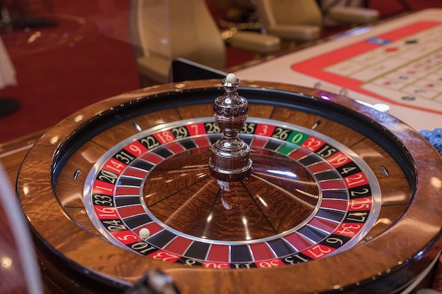 Premium Photo | Roulette table in casino, with many games and slots,  roulette wheel in the foreground. golden and luxury light, casino interior.  gambling is the wagering of money or playing games