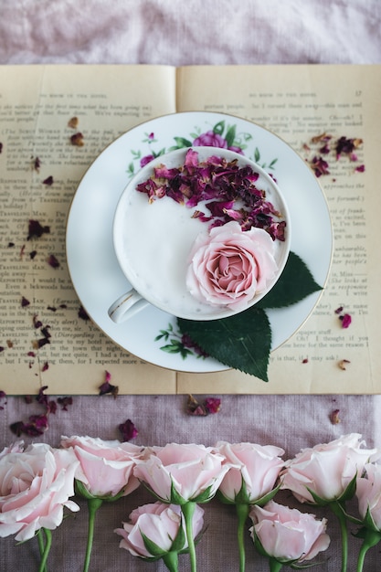 一杯のお茶とバラの丸い白とピンクの花のプレート 無料の写真