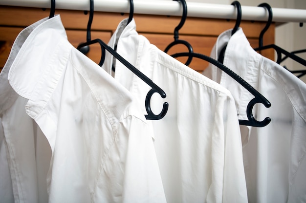 Premium Photo | Row of white cotton clothes hang on black hangers on a ...