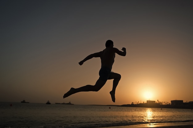 Premium Photo | man. silhouette of running man on sunset fiery sky background in sea, sport and recreation, future and success, people and nature, and healthy lifestyle.