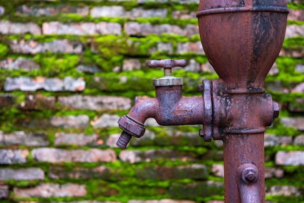 Premium Photo | Rusty old faucet with old brick wall and moss grass