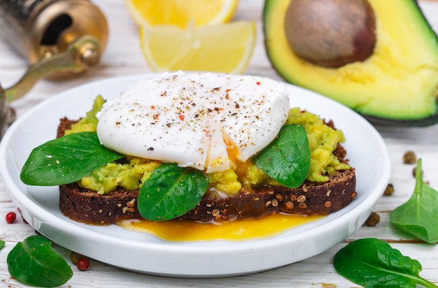 Rye bread toast with coriander, poached egg with green salad spinach Premium Photo