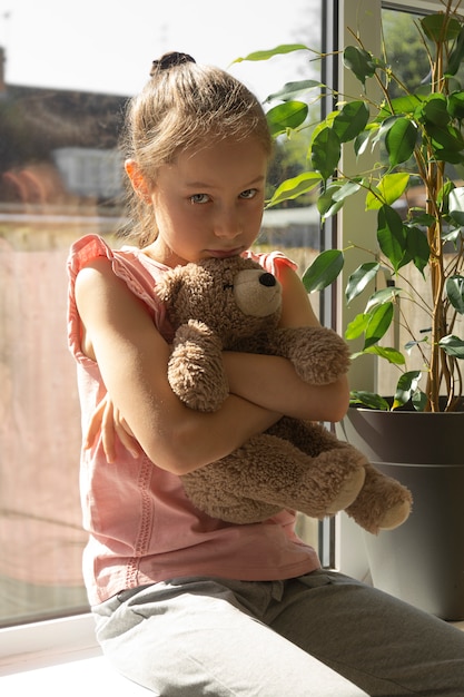 Premium Photo | Sad little girl with her teddy bear at the window.