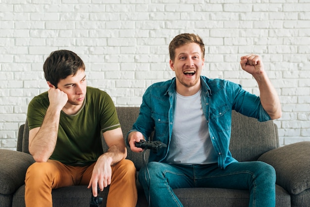 Sad Man Looking At Happy Friend Cheering After Winning The Video