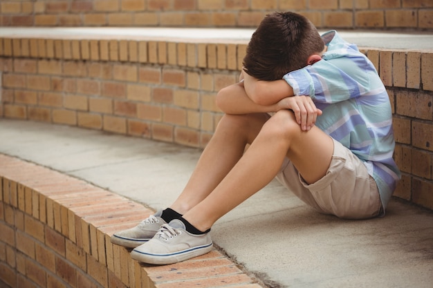 Premium Photo | Sad schoolboy sitting alone on steps in campus