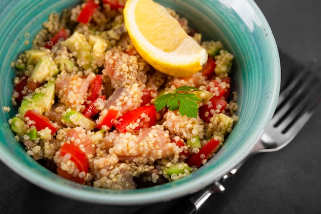 Salmon salad with tomatoes, avocado and quinoa in a blue bowl Premium Photo