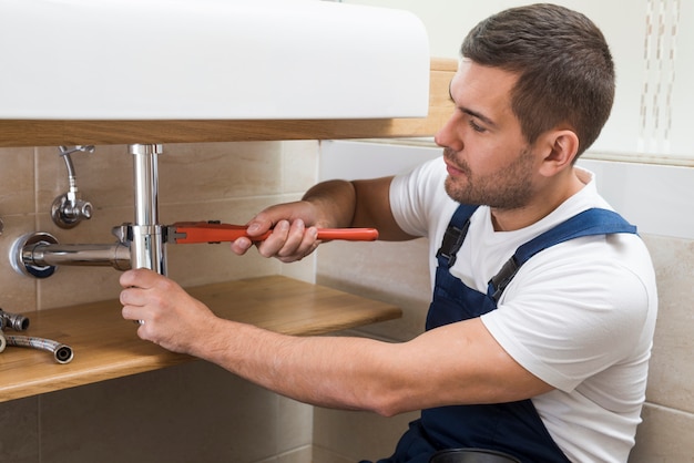 Sanitary technician using wrench on sink Free Photo Sanitary technician using wrench on sink Free Photo