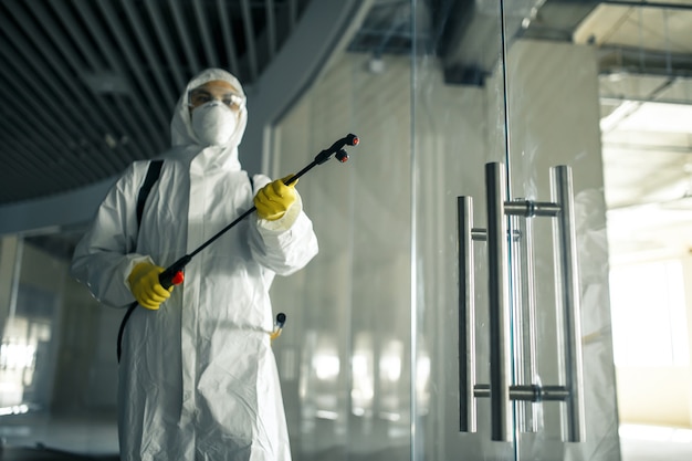 Premium Photo | Sanitary worker sprays an empty business center with ...