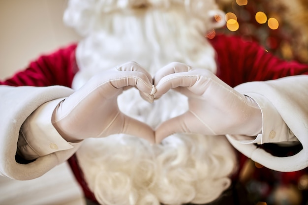 Premium Photo | Santa claus forming shape of heart with her fingers ...