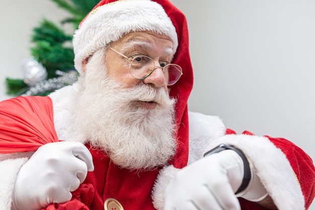 Santa claus is late. he looks scared at the clock. santa claus wears a modern clock. countdown. the time is coming. Premium Photo