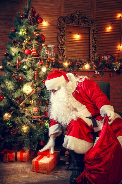 Premium Photo | Santa claus in the living room. santa claus puts gifts ...