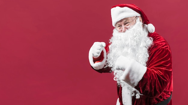 Premium Photo | Santa claus in red hat showing fists