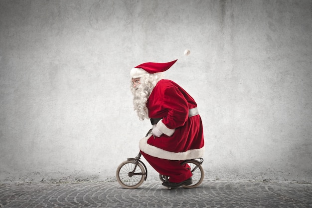 Download Santa claus riding a tiny bike | Premium Photo