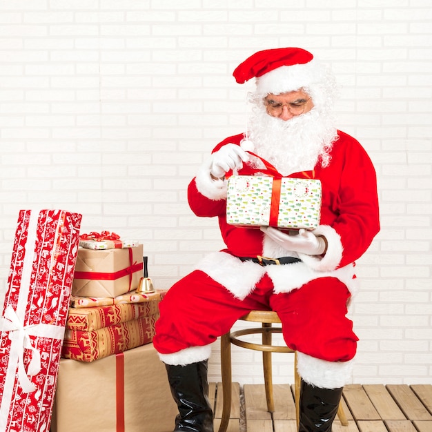 Free Photo | Santa claus sitting and holding present in hands