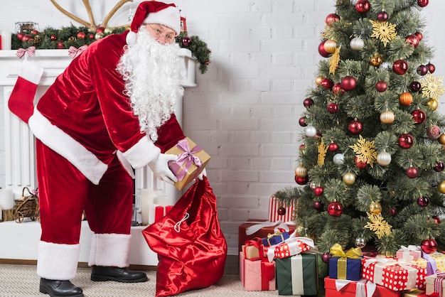 Free Photo Santa Putting Ts Under Christmas Tree 
