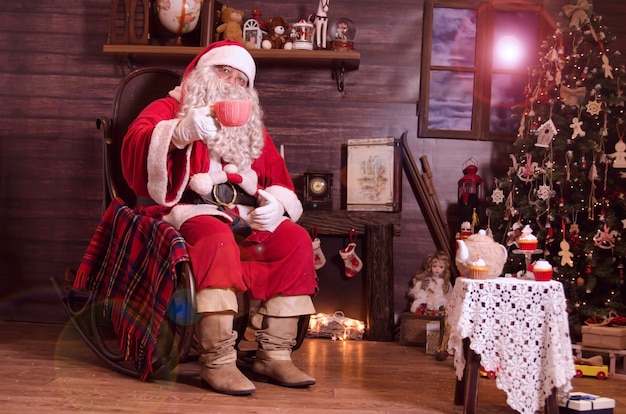 Premium Photo | Santa sitting on rocking chair by the fireplace and ...