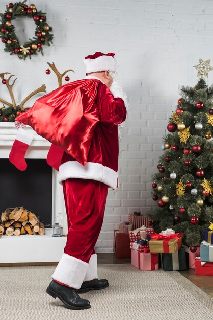 Free Photo | Santa with big sack of gifts behind back going to ...