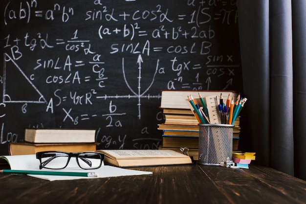 School Desk In Classroom With Books On Background Of Chalk Board