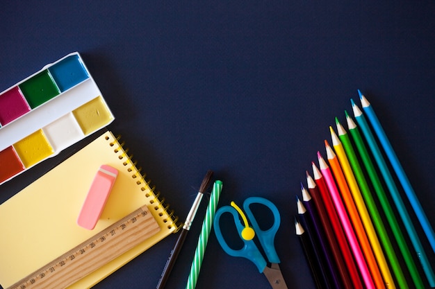 Premium Photo | School supplies on dark blue background.