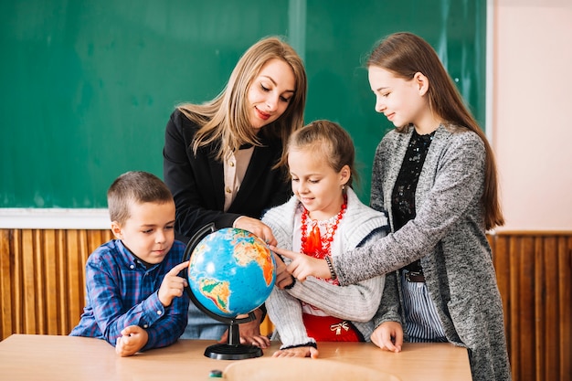 School teacher and students working with globe Free Photo