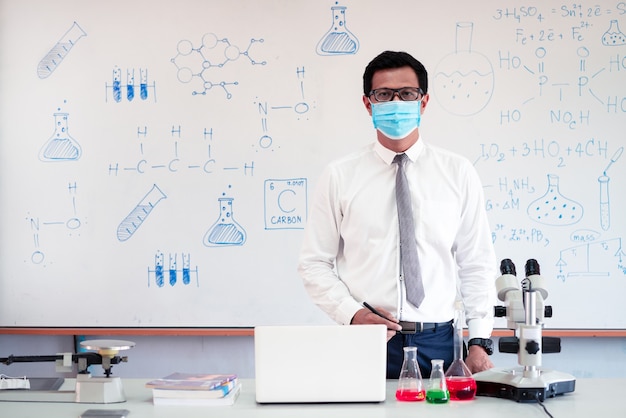 Science chemistry teacher teaching with microscope and laptop in the classroom Premium Photo