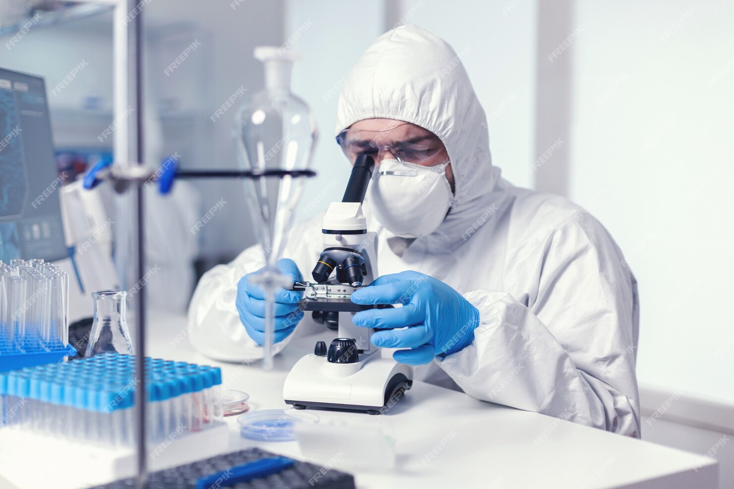 Free Photo | Scientist looking through microscope dressed in ppe suit ...