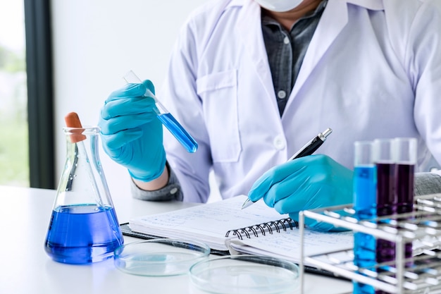 Scientist or medical in lab coat holding test tube with reagent with drop of color liquid Premium Photo