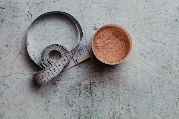 Scoop or spoon of whey protein with visible texture. chocolate flavor. concrete background Premium Photo