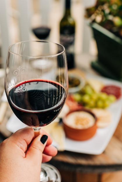 濃い赤ワインで満たされたワイングラスを持つ女性の選択的な垂直クローズアップショット 無料の写真